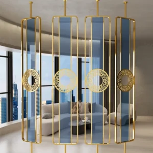 Anat Meesha decorative freestanding room partition with multiple vertical rectangular panels, featuring a gold stainless steel frame, blue transparent glass, and circular gold metal accents with a cut-out design. Luxury divider available near Ambala, Haryana, and across India.