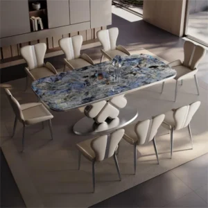 Anat Modern luxury dining set featuring a large rectangular table with a striking blue/gray patterned marble top, a white sculptural base made of heart-shaped modules, and eight matching upholstered dining chairs. Designer furniture available near Ambala, Haryana, and across India.
