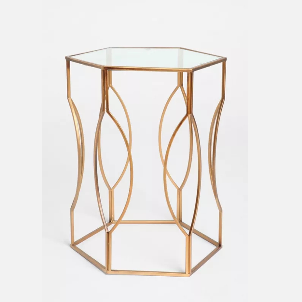 Anat Luxury Hexagonal Glass Side Table Anat Luxury hexagonal side table with a clear glass top and a stylish, intertwined oval-patterned gold metal base. Accent furniture available near Ambala, Haryana, and across India.