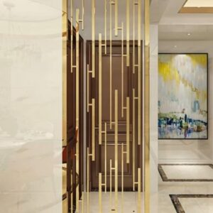 Anat Laser freestanding stainless steel room partition featuring a tall gold metal frame with an intricate geometric pattern of vertical and horizontal laser-cut bars. Luxury divider available near Ambala, Haryana, and across India.