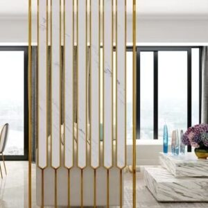 Anat Elara decorative freestanding room partition featuring a vertical gold stainless steel frame and long vertical white marble-look panels with pointed bottom ends. Luxury divider available near Ambala, Haryana, and across India.