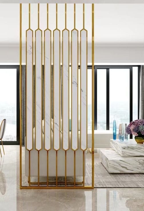 Anat Elara White Stainless Steel Partition Anat Elara decorative freestanding room partition featuring a vertical gold stainless steel frame and long vertical white marble-look panels with pointed bottom ends. Luxury divider available near Ambala, Haryana, and across India.