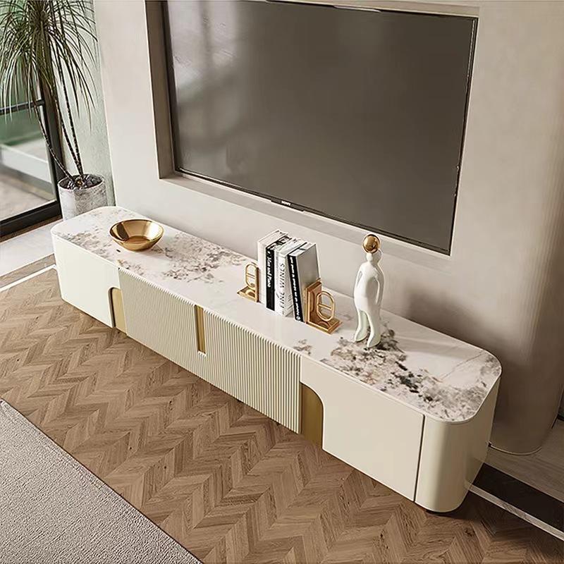 Anat Urbane Gloss TV Stand Anat Urbane luxury TV console unit featuring a long, low profile with a white/cream marble-look top, a central ribbed door/drawer panel, side cut-outs with gold backing, and low gold metal feet. Luxury furniture available near Ambala, Haryana, and across India.