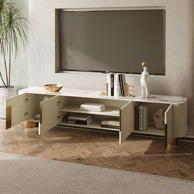 Anat Urbane Gloss TV Stand Anat Urbane luxury TV console unit featuring a long, low profile with a white/cream marble-look top, a central ribbed door/drawer panel, side cut-outs with gold backing, and low gold metal feet. Luxury furniture available near Ambala, Haryana, and across India.