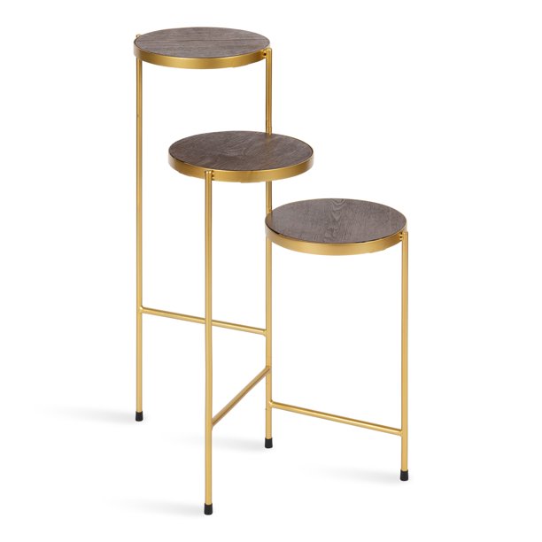 Anat Oria Tiered Display Stand Anat Oria modern three-tiered display stand featuring thin gold metal legs and three round shelves with a dark brown or bronze finish, set at staggered heights. Decorative furniture available near Ambala, Haryana, and across India.