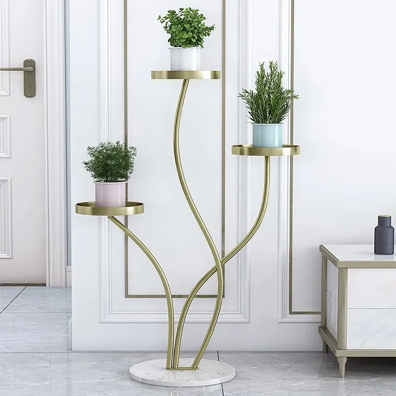 Anat Verona modern three-tiered indoor plant stand featuring three gracefully curving gold metal stems supporting round gold tray shelves, anchored by a round white marble base. Decorative furniture available near Ambala, Haryana, and across India.