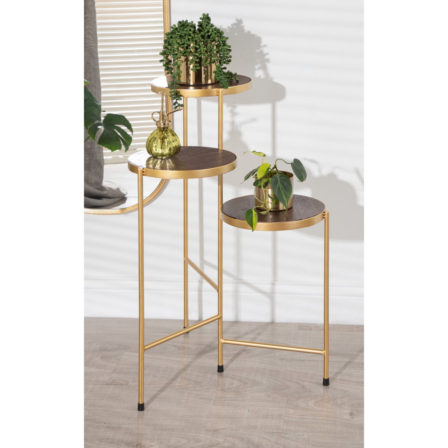 Anat Oria Tiered Display Stand Anat Oria modern three-tiered display stand featuring thin gold metal legs and three round shelves with a dark brown or bronze finish, set at staggered heights. Decorative furniture available near Ambala, Haryana, and across India.