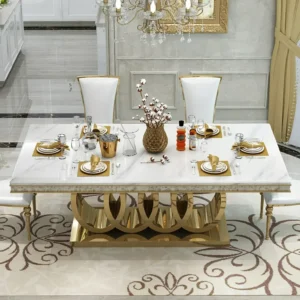 Anat Audi luxury dining set featuring a large rectangular white marble-look top, a highly decorative gold stainless steel base with a semicircular design, and high-back white upholstered dining chairs. Designer furniture available near Ambala, Haryana, and across India.