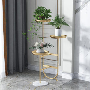 Anat Solis modern triple-tier plant stand featuring a tall gold metal frame with three round tray-style shelves at varying heights, supported by a round white marble base. Decorative furniture available near Ambala, Haryana, and across India.