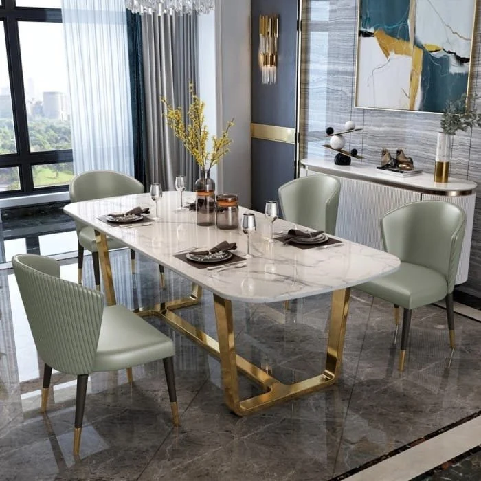 Anat Opulent Luxe Dining Ensemble Anat Opulent Luxe modern dining set featuring a rectangular white marble-look top, a polished gold metal base, and six sage green/gray upholstered dining chairs. Luxury dining furniture available near Ambala, Haryana, and across India.